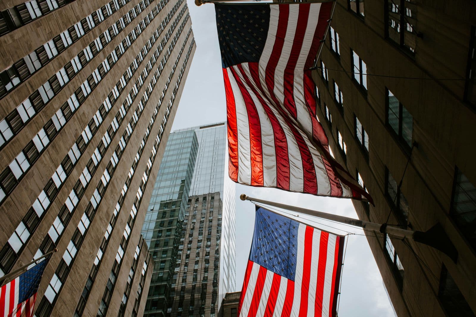 Bandeiras dos Estados Unidos penduradas entre arranha-céus, vistas de baixo