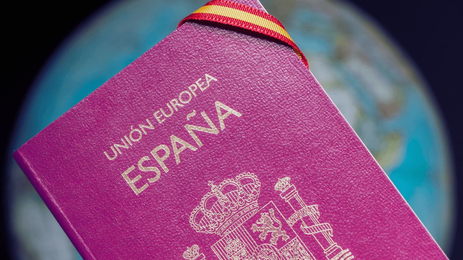 Passaporte espanhol em close, com um globo terrestre desfocado ao fundo