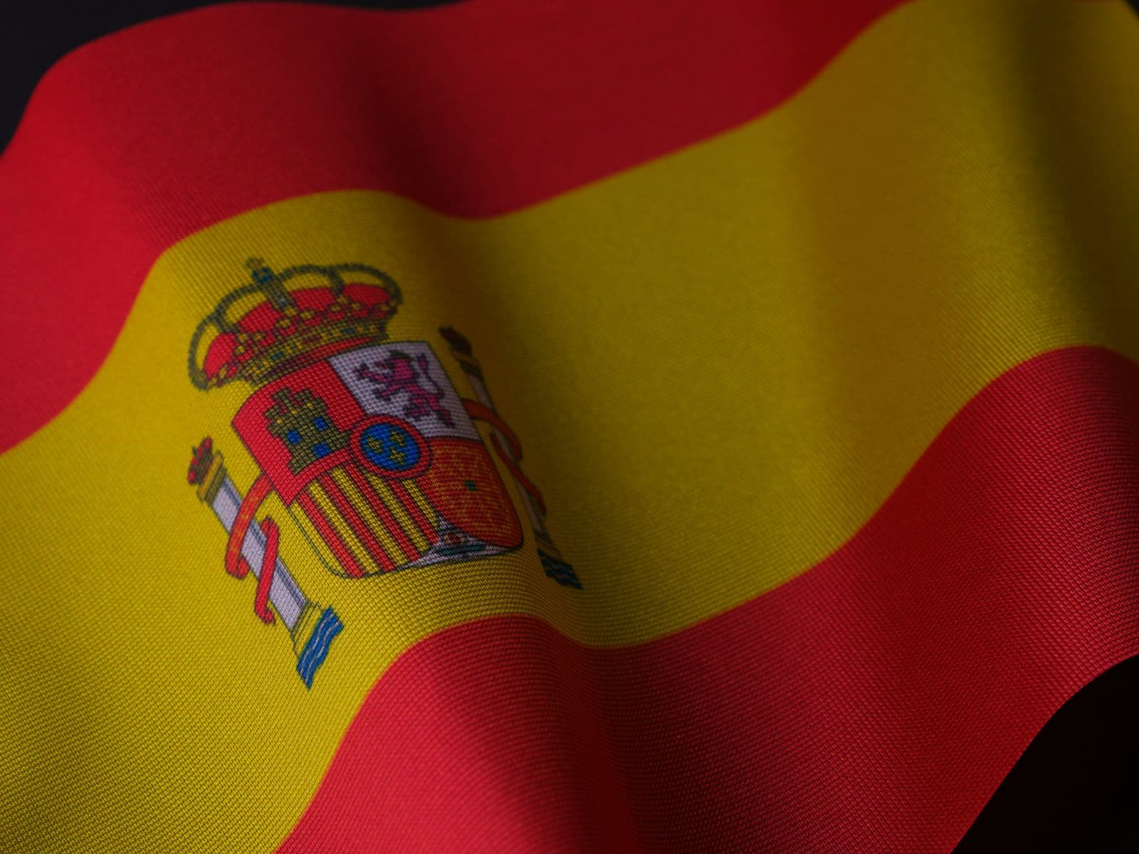 Bandeira da Espanha em close, com o brasão nacional sobre as faixas vermelha e amarela