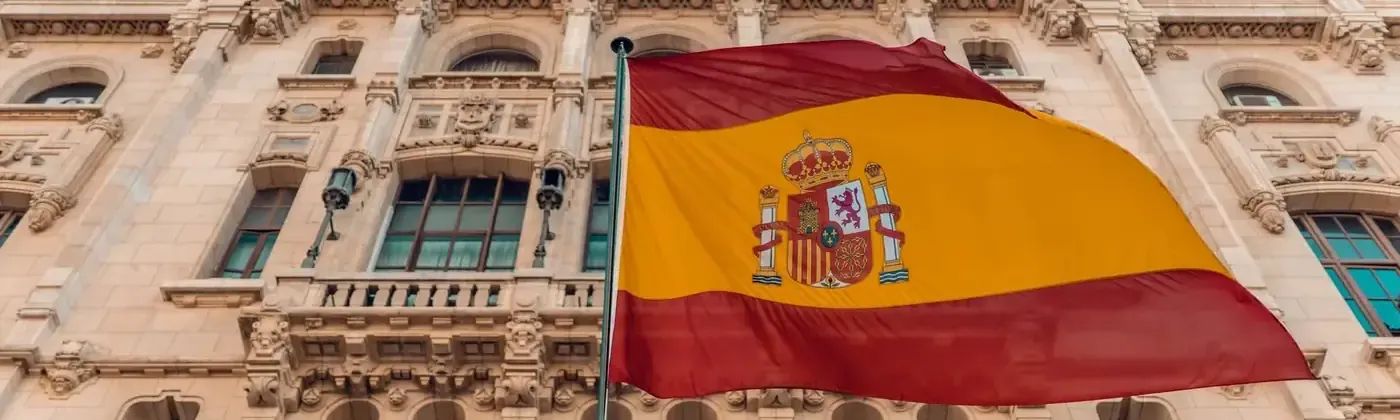 Bandeira da Espanha tremulando diante da fachada de pedra de um edifício em Madri