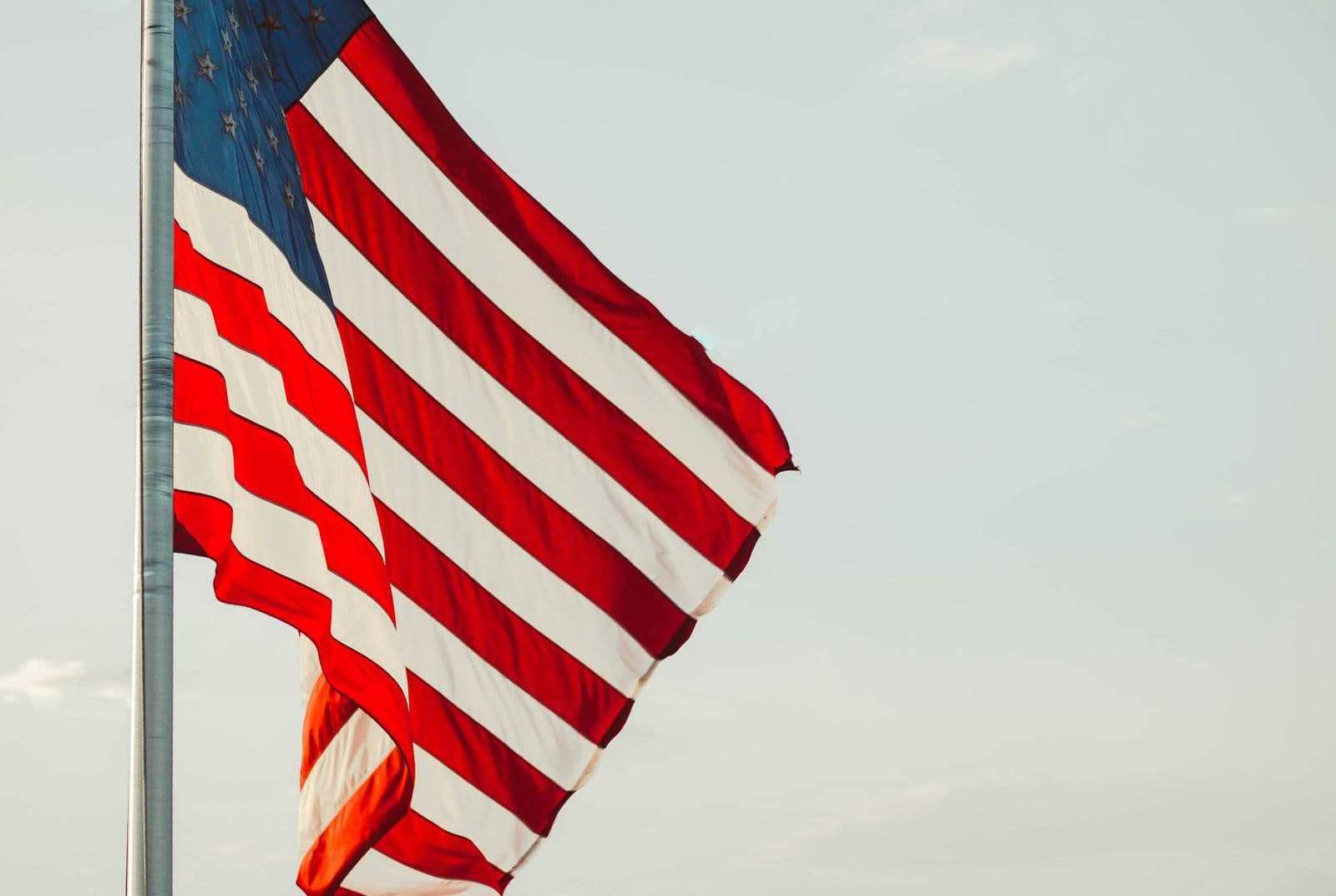 Bandeira dos Estados Unidos tremulando em um mastro, contra o céu claro