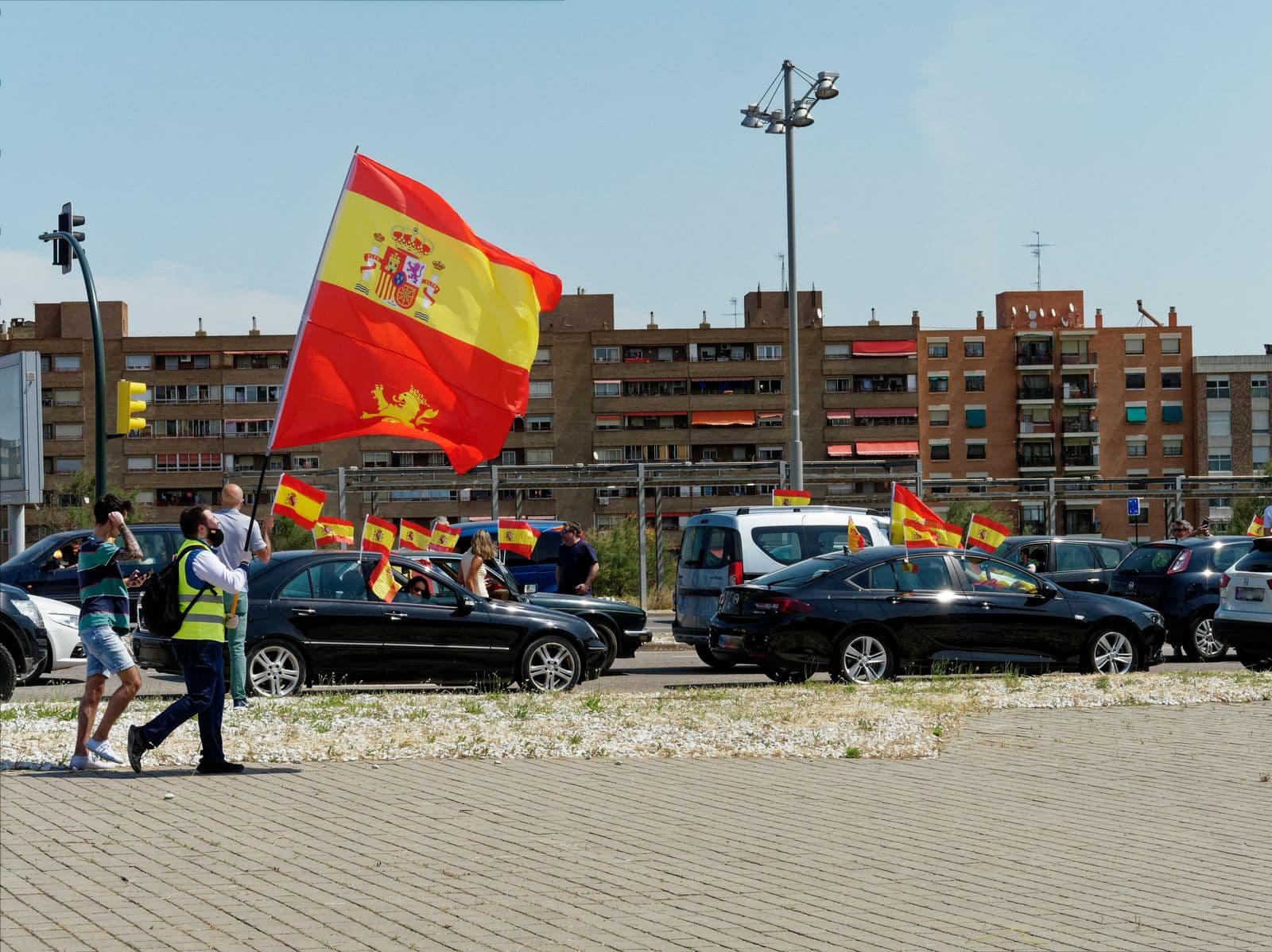 Manifestação com carros na rua e pessoas empunhando bandeiras da Espanha