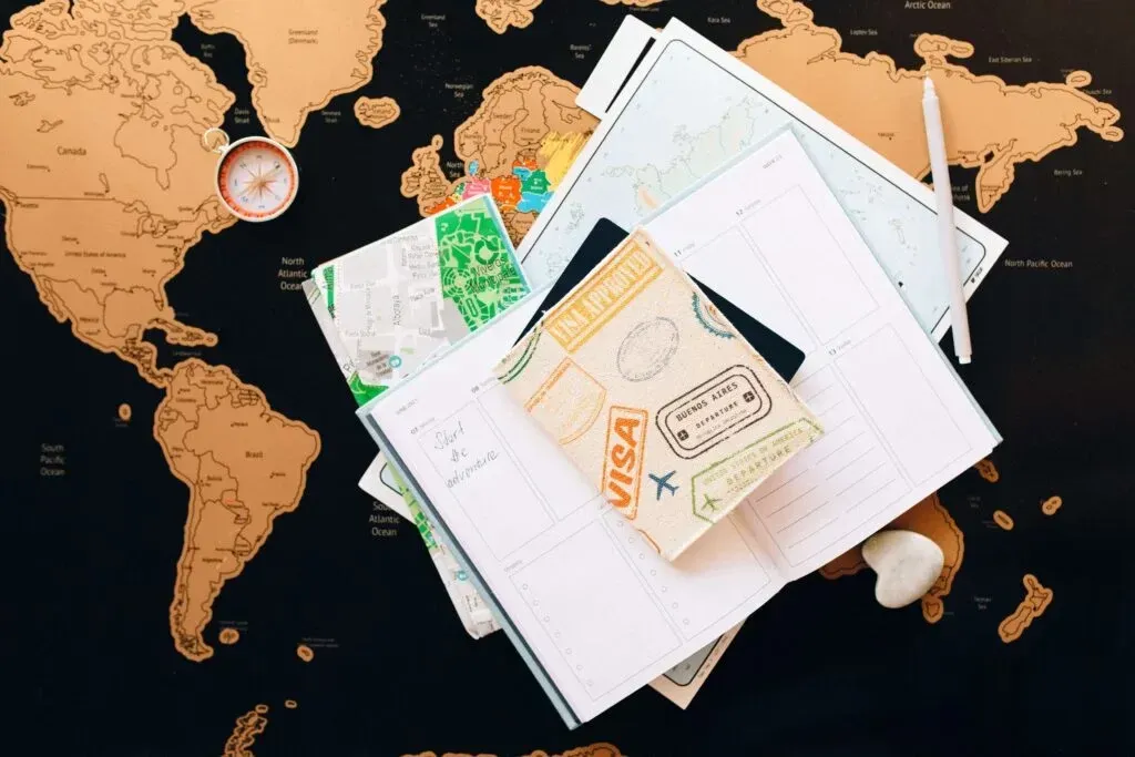 Passaporte, vistos e mapas espalhados sobre um mapa-múndi
